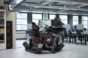 Fahrsimulator im Akustilabor bestehend aus einer Bewegungsplattform, einem Fahrersitz, 3 Monitoren sowie Lautsprechern.