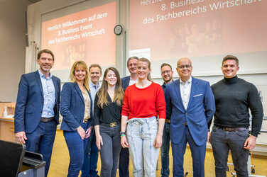 Gruppenfoto mit Mitarbeitern des Fachbereichs Wirtschaft und Unternehmensvertreter:innen in einem Hörsaal.