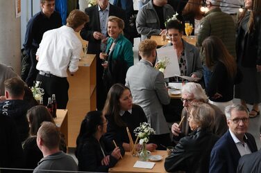 Blick in das mit Gästen gefüllte Foyer des Fachbereichs, die an Stehtischen stehen.