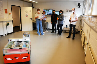 A group looks at a mobile robot in IDiAL's robot lab.