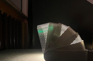 Eine Lampe aus weißem, zum Teil gelochten Metall.