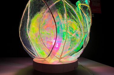 Eine blütenförmige Lampe leuchtet, umgeben von Dunkelheit.