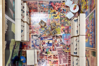 View from above into the miniature model of a comic store, the floor of which is covered with comic motifs.