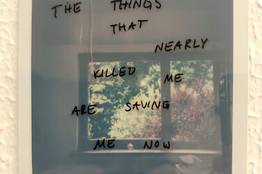 Ein Polaroid mit handschriftlicher Aufschrift "The Things That Nearly Killed Me Are Saving Me Now"