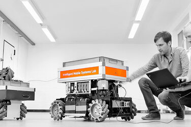 Two students work on a mobile robot system.