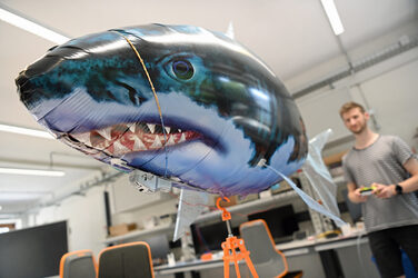 One person controls a balloon shark.