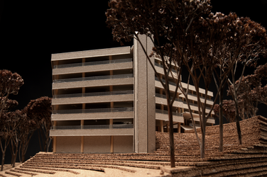 Eine detailreiche Nahaufnahme zeigt die Fassade des Modellgebäudes mit Terrassen und Stützen. Im Vordergrund stehen modellierte Bäume auf gestuften Geländeschichten.