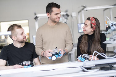 Three students work together on a group task in the lean lab.