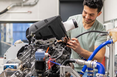 Ein Bild, das einen Studenten zeigt, der an einer technischen Maschine arbeitet