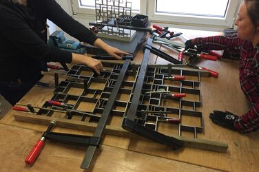 Students assemble the individual parts of their railing on a table.