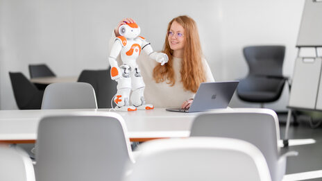Studentin mit einem Roboter und Laptop