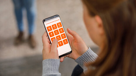 Photo over the shoulder of a student on her smartphone, the app from Fachhochschule Dortmund is open __Young woman is typing on the smartphone, the app from Fachhochschule Dortmund is open.