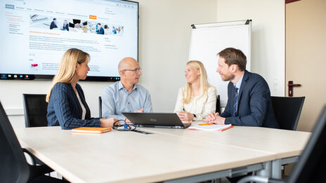 Four professors are sitting at a table having a lively conversation.