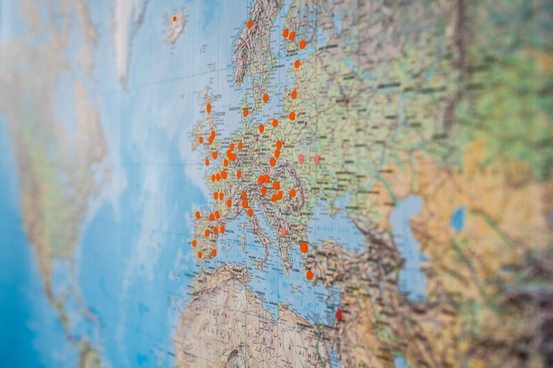 Close-up of a world map on which places are marked with orange dots.