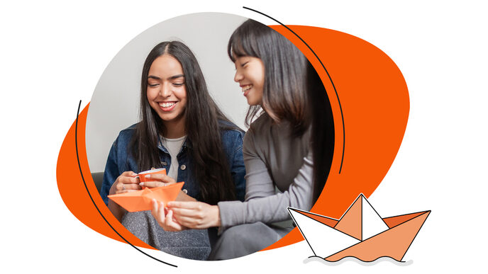 Two female students sit on a sofa or armchair and laugh while folding an orange paper boat; next to them is a stylized depiction of a floating paper boat.