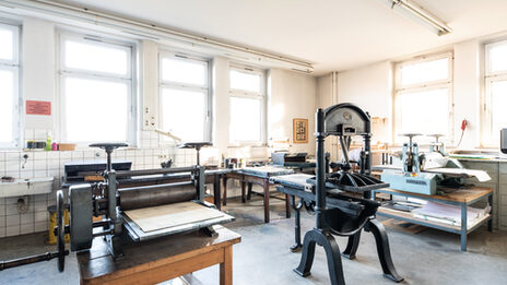 Photograph of the printing workshop with various large presses and printing equipment.