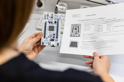 Photo of a woman holding a development board in one hand and a task sheet in the other.