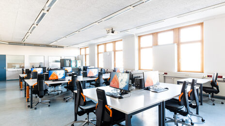 Room shot of the laboratory for networks and operating systems, with several rows or groups of tables equipped with computers.