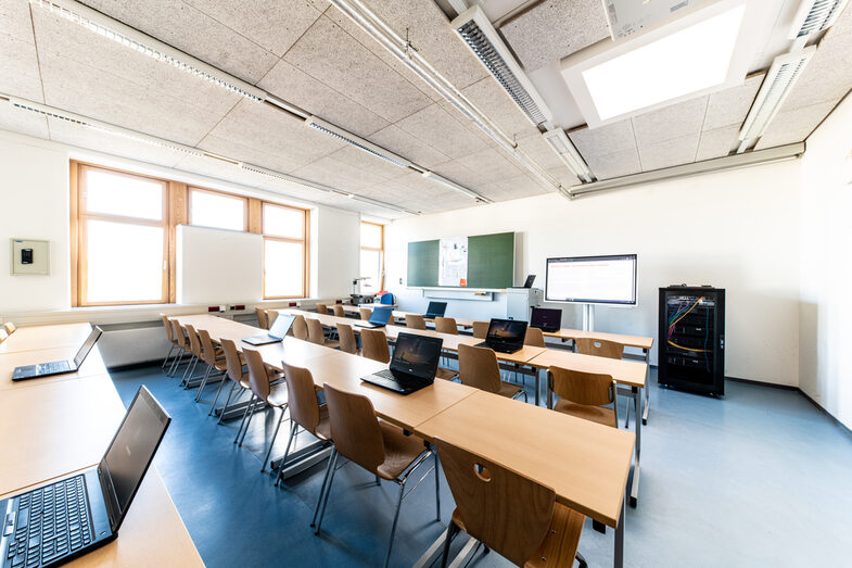 Photo of a mobile lab with laptops in a seminar room. There is a monitor and a server desk in front.