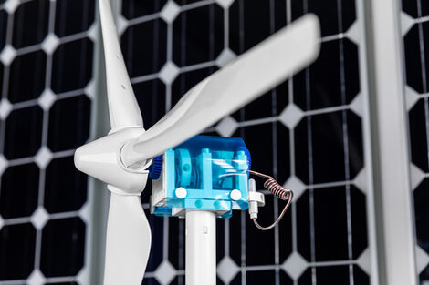 Close-up of a miniature wind turbine, a solar cell in the background.