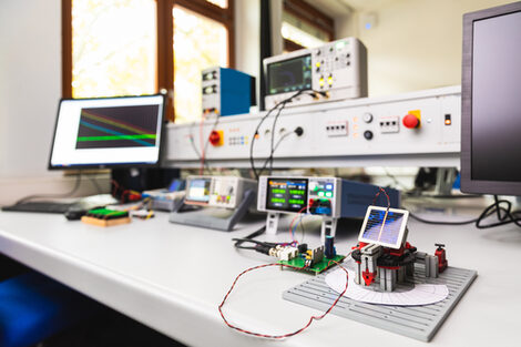 Photo of an experimental setup with a solar cell. Measuring devices and screens are set up on a table, the solar cell can be seen in the foreground.