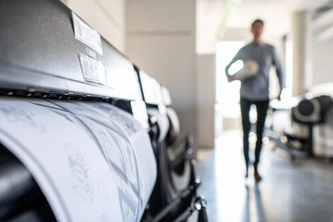 Side close-up of printing something for the Faculty of Architecture. A man walking down the corridor is out of focus on the right.