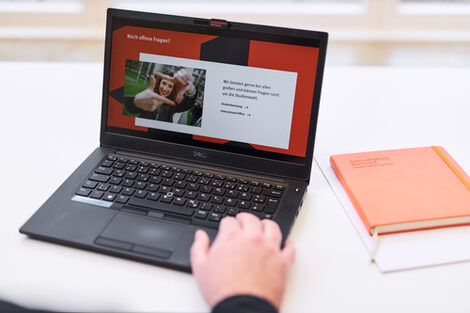 Photo of a laptop on which the slide of a presentation with the heading "Any questions?" is displayed. A person's hand is on the keyboard.