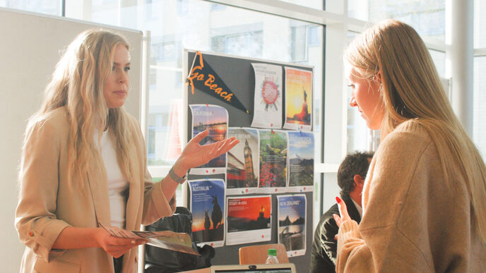 Zwei junge Frauen unterhalten sich im Sonnenschein an einem internationalen Messestand beim "Marktplatz der Möglichkeiten"__Two young women chat in the sunshine at an international trade fair stand at the "Marketplace of Opportunities"