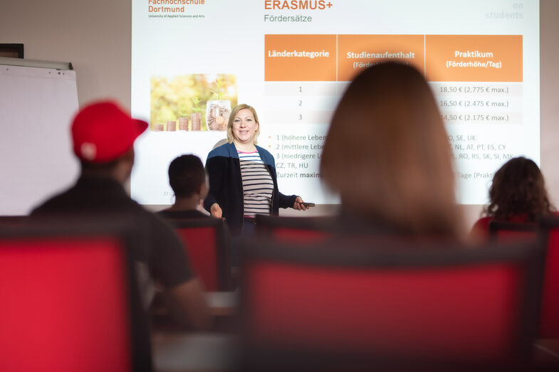 Photo of an information event organized by the International Office in a lecture hall. A lecturer stands in front of a projected slide on the subject of "Erasmus".