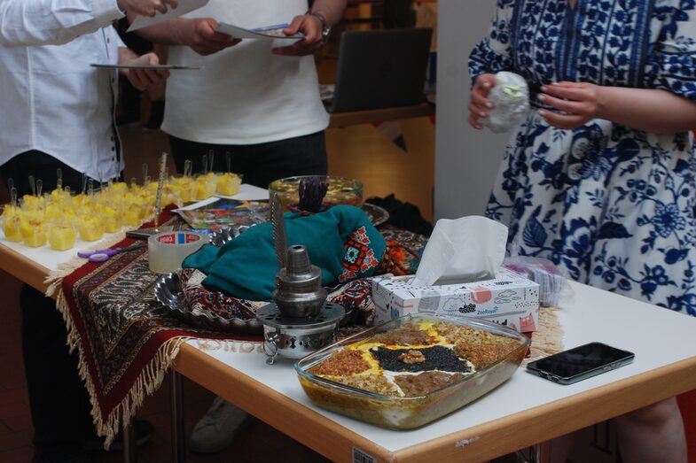 Cultural stand Iran: People standing around a table with food.