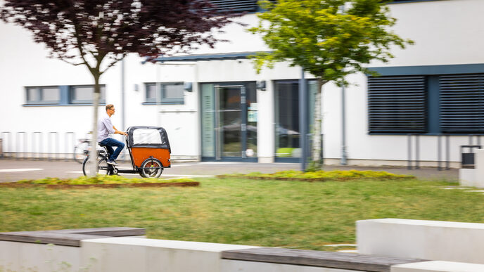 Photo Photo of a man riding a cargo bike on the FH campus.