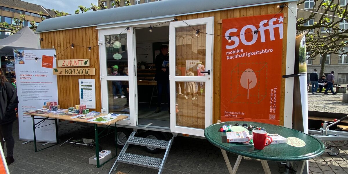 Ein umgebauter Bauwagen der nun als mobiles Nachhaltigkeitsbüro dient, steht auf einem Platz zur Ausstellung.