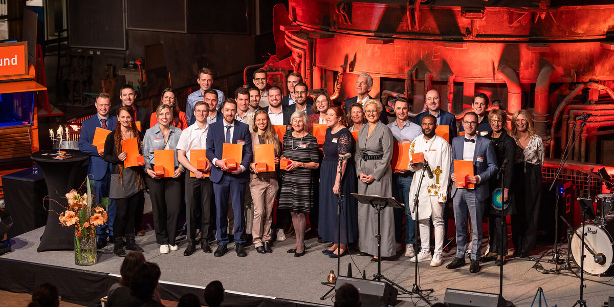 Many people stand on the stage with certificates in their hands.