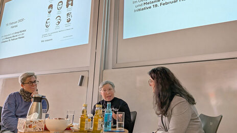 People talking to each other in front of a screen in a lecture hall.