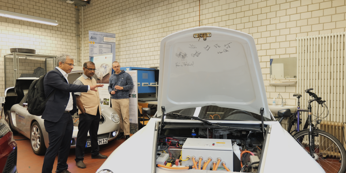 Three people stand between several cars in a laboratory at the Faculty of Mechanical Engineering.