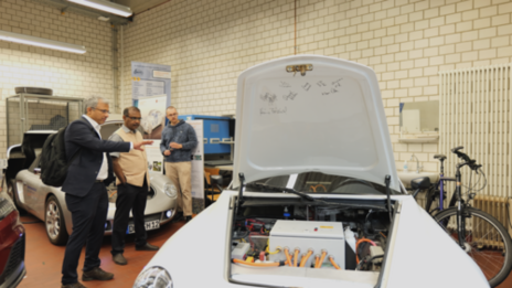 Three people stand between several cars in a laboratory at the Faculty of Mechanical Engineering.