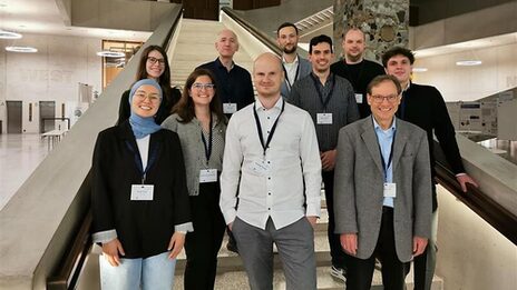 A group of people are standing on a staircase in a foyer.