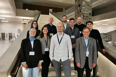 A group of people are standing on a staircase in a foyer.