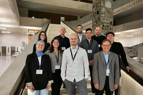 Einen Gruppe Menschen steht in einem Foyer auf einer Treppe.