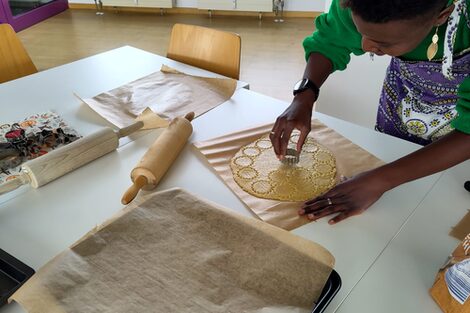 Eine Person sticht Kekse in Sternform aus einem Teig aus.