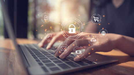 A photo of a woman working on a laptop. In the foreground you can see various symbols representing data protection.