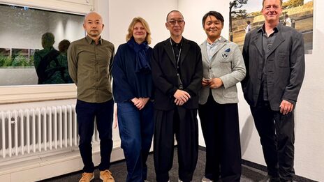 Five people in an interior look friendly towards the camera.