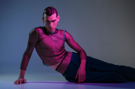 A fashion photograph of a male read in a mesh top.