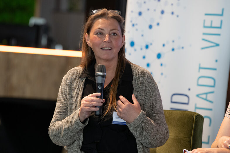 Close-up of Prof. Dr. Sabine Sachweh. She has a microphone in her hand and is speaking at the panel discussion.