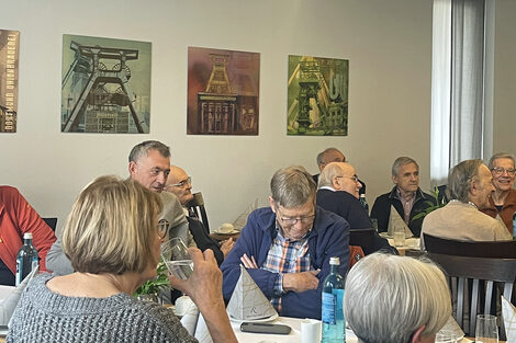 Menschen sitzen an Tischen und unterhalten sich.