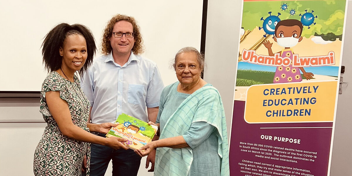 Three people are standing next to each other. One person is holding a coloring book.