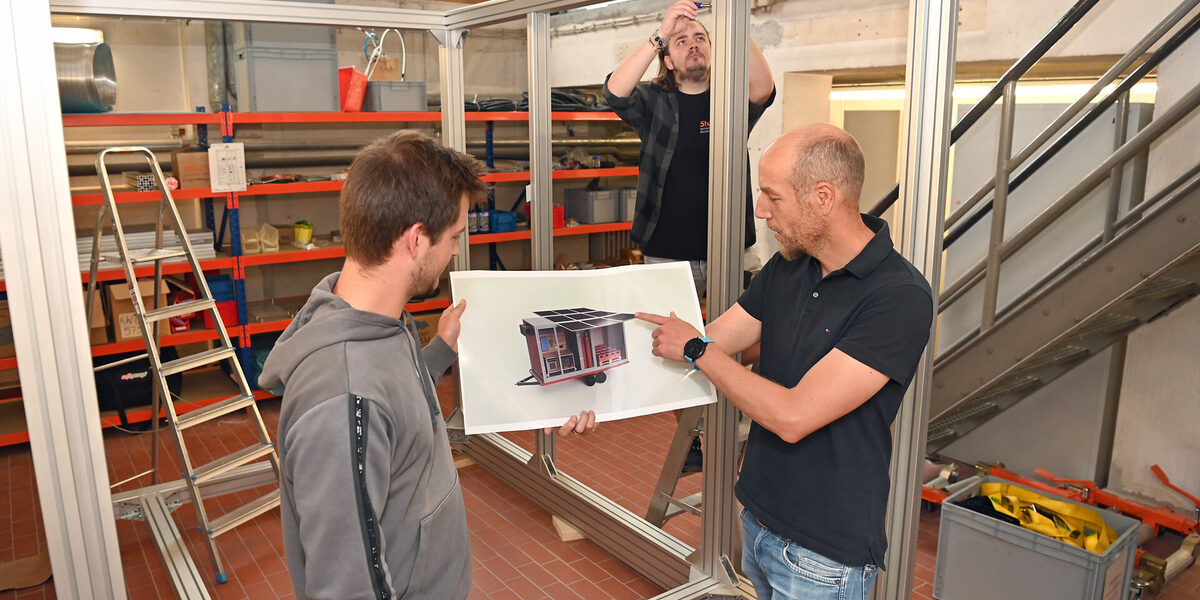 Drei Menschen stehen in einer Werkstatt