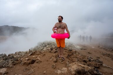 Auf dem Bild ist ein Mitglied des MSG-Kollektivs in einem natürlichen Pool in Island zu sehen. Das Bild ist inszeniert, u.a. mit einem rosa Schwimmreifen