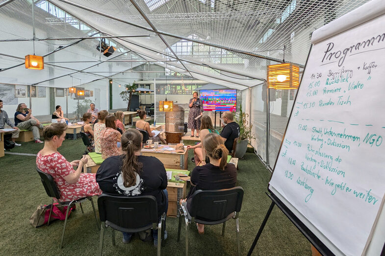 People sit in front of a small stage and listen to someone