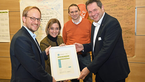 Four people hold a certificate